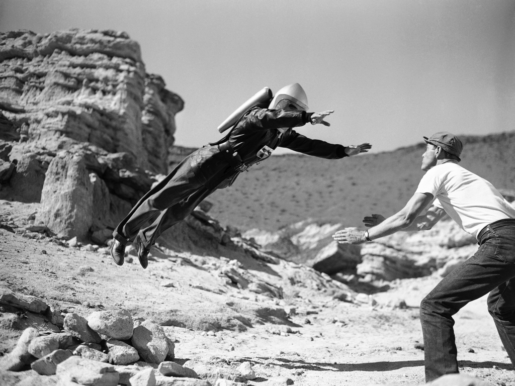 "Commando Cody, the Sky Marshal of the Universe," aka, George Wallace, appears to defy the laws of gravity, for a moment at least, as he lands in the arms of a prop man during production of the film " Radar Men from the Moon," at Red Rock Canyon in the Mojave Desert, 80 miles northeast of Hollywood, Calif., Dec. 12, 1951. Gravity may be defied in some the new movie serials based on the fantasies science fiction, but what goes up still comes down, even if the film wont let you see it. (AP Photo)